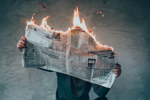 Човек държи горящ вестник